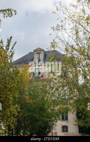 Paris, Frankreich, 2023. Die Fassade der Bibliothèque de l'Arsenal im Blick durch das Laub der Bäume im Jardin Teilhard de Chardin (vertikal) Stockfoto