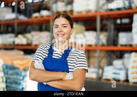 Positiver Lagermädchen steht mit überkreuzten Armen über der Brust. Stockfoto