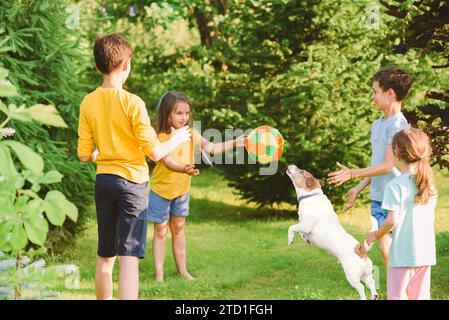 Eine Gruppe von Kindern wirft und fängt einen Ball, während sie mit einem Hund das Spiel „Affe in der Mitte“ spielen Stockfoto