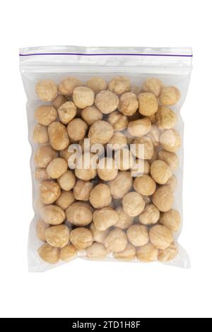 Haufen gerösteter geschälter Haselnüsse isoliert auf weißem Hintergrund, Draufsicht, Konzept des gesunden Frühstücks, veganes Essen, getrocknete Nüsse in transparentem Paket Stockfoto