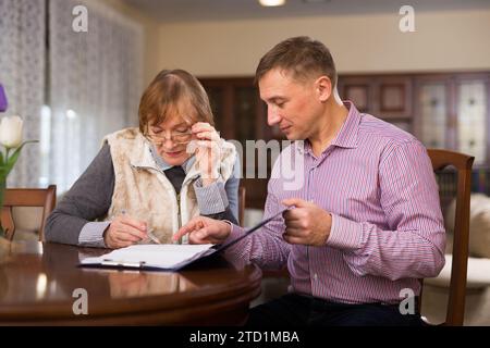 Frau mit Sohn, die Dokumente ausfüllt Stockfoto