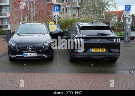 Coevorden, Niederlande - 5. November 2023 zwei schwarze Elektroautos laden ihre Batterien auf. Einer ist ein Mercedes EQA, der andere ein Ford Mustang Mac Stockfoto