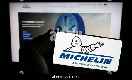 Person mit Smartphone und Logo der Compagnie Générale des établissements Michelin SCA vor der Website. Schwerpunkt auf dem Display des Telefons. Stockfoto