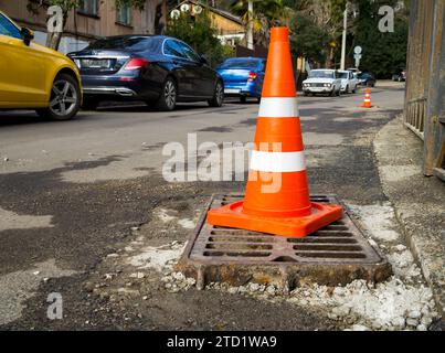 Sotschi, Russland - 16. Februar 2023: Markiert durch einen Kegel, der vorstehende Teil eines Sturmgitters auf einer Straße, die repariert wird Stockfoto