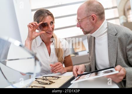Kunde untersucht Sonnenbrillen-Linse für Brillen mit einem Optiker in einem Optikgeschäft Stockfoto