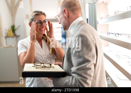 Frau beim Anprobieren neuer Brillen mit Augenoptiker in einem Optikgeschäft. Stockfoto