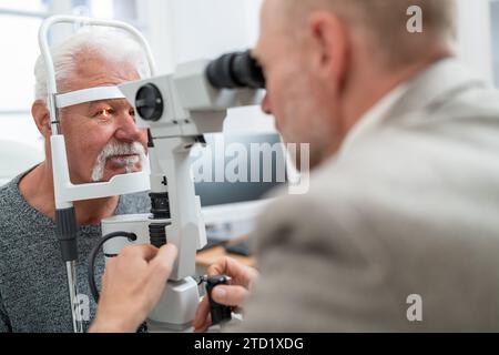 Optometrist mit einer Spaltlampe, um das Auge eines Seniorenmannes in der Klinik zu untersuchen. Nahaufnahme. Gesundheitswesen und Medizinkonzept Stockfoto