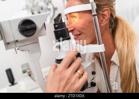 Weibliche Patientin, die sich einer Augenuntersuchung mit Fokus auf ihr beleuchtetes Auge mit einer Spaltlampe in der Klinik unterzieht. Nahaufnahme. Gesundheitswesen und Medizin Stockfoto