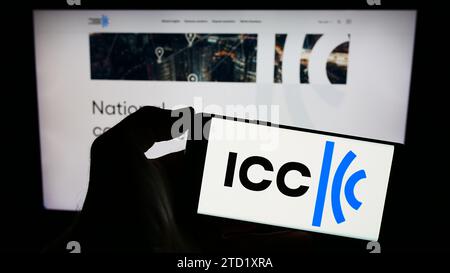 Person mit Mobiltelefon und Logo der Organisation International Chamber of Commerce (ICC) vor der Webseite. Schwerpunkt auf dem Display des Telefons. Stockfoto