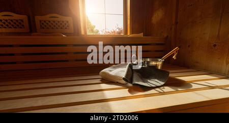 Holzsauna mit Bänken, Fenster, Handtuch, Metalleimer, Kelle, und Filzhüte in einer finnischen Sauna. Konzept Spa Wellness Hotel. Stockfoto