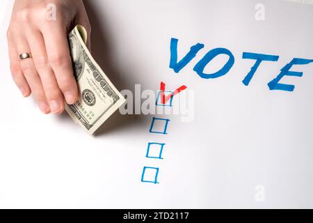 Kauf Stimmen der Wähler Konzept. Eine Frau hält einhundert US-Dollar auf dem Hintergrund des Wortes vote. Stockfoto