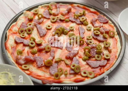 Ungebackene Pizza mit Belag auf einem Metalltablett. Stockfoto