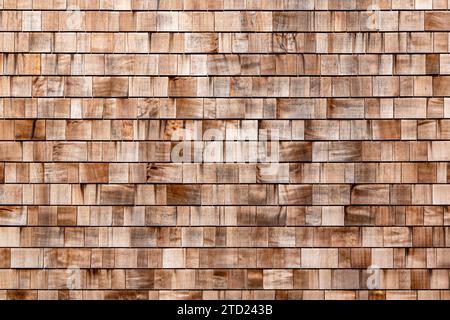 Hauswand mit kleinen Holzfliesen als Hintergrund bedeckt. Alte braune rustikale dunkelbraune Holzschindeln Wandstruktur. Hintergrund der Wand mit Holzschütteln. Zedernsteinplatte an der Außenwand schleifen Stockfoto