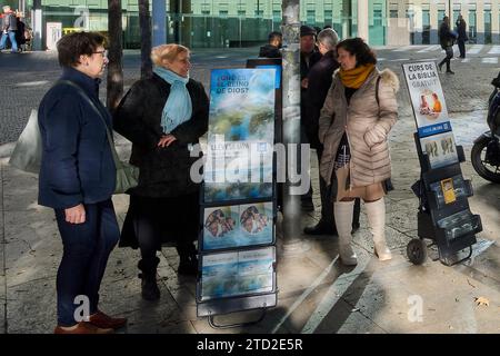 Barcelona - 15. Dezember 2023: Gruppe von Menschen, die sich auf einer städtischen Straße neben einer religiösen Werbung in der Justizstadt Barcelona unterhalten Stockfoto