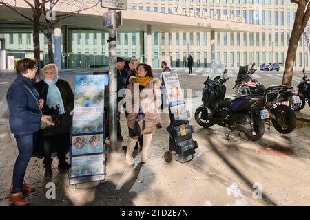 Barcelona - 15. Dezember 2023: Gruppe von Menschen, die sich auf einer städtischen Straße neben einer religiösen Werbung in der Justizstadt Barcelona unterhalten Stockfoto