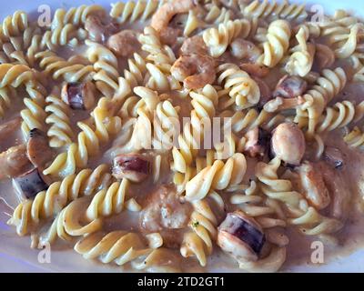 Köstliches Fusilli-Pastagericht in cremiger Sauce mit Meeresfrüchten wie Garnelen und Tintenfischen Stockfoto