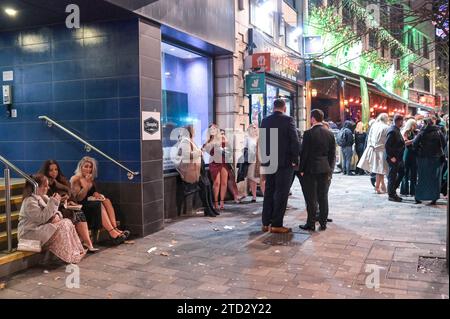 Broad Street, Birmingham 16. Dezember 2023 - die Nachtschwärmer haben am Freitag, den 15. Dezember Abend in Birmingham den berüchtigten Nachtclub-Strip besucht, als sie den vorletzten Freitag vor Weihnachten genossen. Mehrere Partygäste trugen Weihnachtsoutfits und eine Arbeitsfeier voller Santas, die für ein Gruppenfoto posierten, bevor sie sich auf den Weg zu einem anderen Pub machten. Freunde trugen einander entlang des Nachtlebens der Broad Street, als der Abend in den Morgen verwandelte. Andere wurden in Smart Wear gesehen, nachdem sie festliche Galas im Stadtzentrum besucht hatten. Viele Leute zeigten ihre Weihnachtspullover, während sie milde Temperaturen genossen. Die Stockfoto