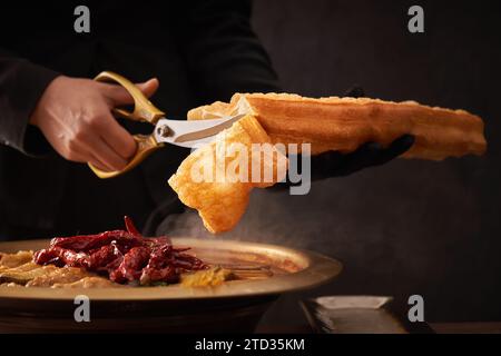 Gedünsteter Karpfenfischkopf in brauner Sauce serviert mit frittiertem Teigstock Stockfoto