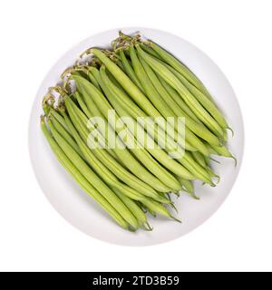 Frische grüne Bohnen in einer weißen Schüssel. Junge, unreife Früchte einer Sorte der gewöhnlichen Bohnen oder auch der französischen Bohnen Phaseolus vulgaris. Nahaufnahme, isoliert. Stockfoto