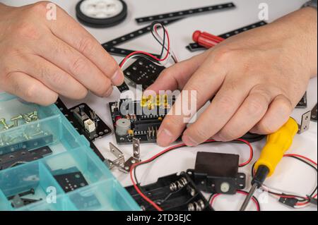 Nahaufnahme von Händen, die Robotik-Lehrspielzeug zusammenbauen. MINT-Bildungskonzept Stockfoto