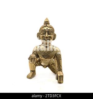 Goldene Vintage-Figur des krabbelnden Baby-Lord krishna, auch gopal genannt, mit süßem Laddu in der Hand isoliert auf einem weißen Hintergrund Stockfoto