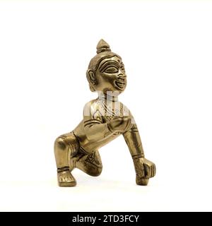 Goldene Vintage-Figur des krabbelnden Baby-Lord krishna, auch gopal genannt, mit süßem Laddu in der Hand isoliert auf einem weißen Hintergrund Stockfoto