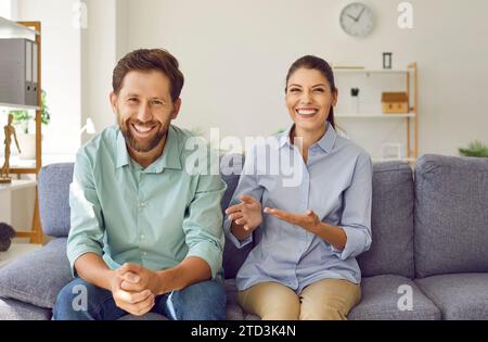 Glückliches Paar, das in die Kamera schaut und lächelt, führt Videoanrufe und chattet mit Freunden online. Stockfoto