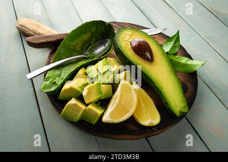 Reife, frische Avocadoscheiben auf einem Holzteller mit Zitrone. Konzept für gesunde Ernährung. Lebensmittelfotografie Stockfoto