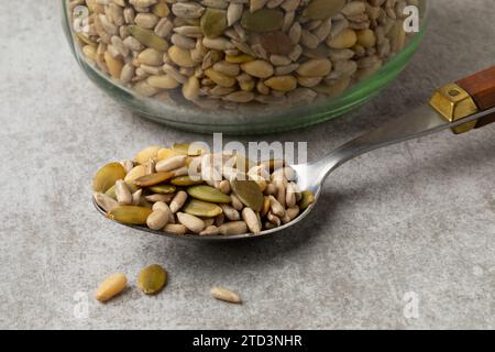 Mischung aus getrockneten Salatkernen auf einem Löffel vor einem Glasgefäß Stockfoto