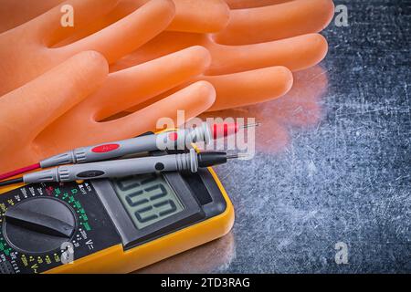 Digitales elektrisches Prüfgerät isolierende Gummihandschuhe auf metallischem Hintergrund Stockfoto