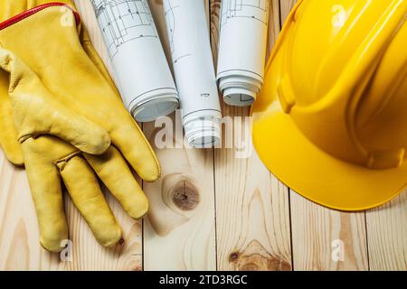 Gelbe Handschuhe Blaupausen und Bauhelm auf Holz Stockfoto