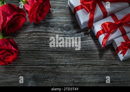 Weiße Geschenkbox mit duftenden roten Rosen auf Holzbrett Stockfoto