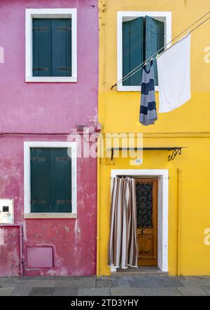 Lila und gelbe Hausfassade mit Eingangstür und Fenstern und Wäscheleinen, farbenfrohe Häuser auf der Insel Burano, Venedig, Venetien, Italien Stockfoto