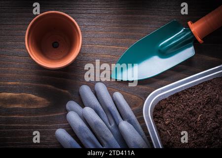 Handspaten Arbeitshandschuhe Gartentablett mit Boden und Tontopf auf Vintage Holzbrett Landwirtschaftskonzept Stockfoto