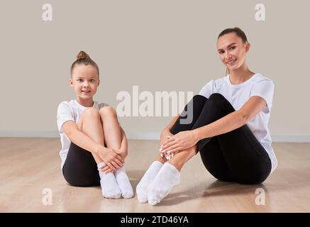 Schöne Lehrerin posiert mit einem kleinen Mädchen in einem Gymnastikkurs. Das Konzept der Bildung, Sport, Pilates, Stretching, gesunde Lebensweise. Stockfoto