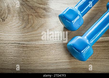 Blaue Hantelgewichte auf Holzbrett-Fitnesskonzept Stockfoto