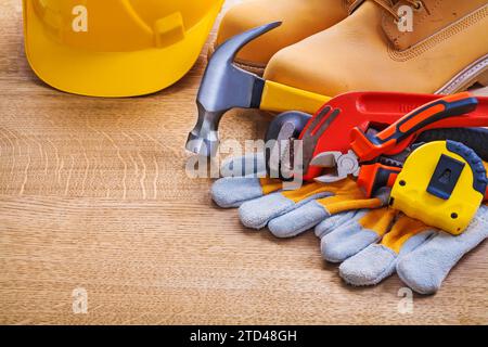 Horizontale Ansicht Helm Stiefel Handschuh Tapeline Affenschlüssel Hammerzange auf Holzbrett Stockfoto