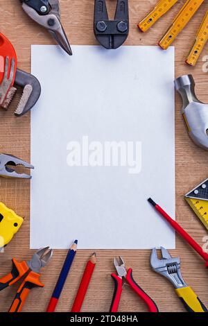 Organisierte Kopierfläche weißes Papier und Cutter Meter Hammer Rollschraubendreher Zange Bleistift Tapeline Schraubenschlüssel auf Holzbrett Stockfoto