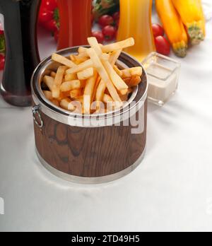 Frische Pommes frites auf einem Holzeimer mit einer Auswahl an Bieren und frischem Gemüse im Hintergrund, Lebensmittelfotografie Stockfoto