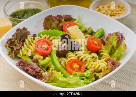 Frischer, gesunder, hausgemachter italienischer Fusilli-Pasta-Salat mit Parmesan, pachino-Kirschtomaten, schwarzen Oliven und gemischtem Gemüse, gewürzt mit Stockfoto