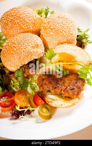 Vier frische und leckere Mini-Hähnchenburger auf einem Teller, Nahaufnahme, Lebensmittelfotografie Stockfoto