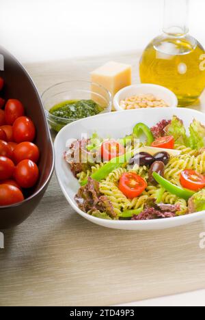 Frischer, gesunder, hausgemachter italienischer Fusilli-Pasta-Salat mit Parmesan, pachino-Kirschtomaten, schwarzen Oliven und gemischtem Gemüse, gewürzt mit Stockfoto