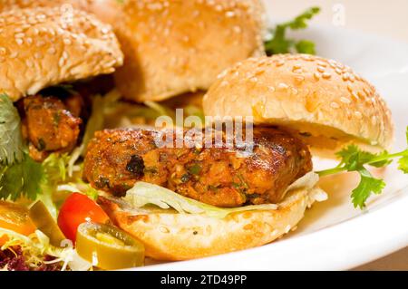 Vier frische und leckere Mini-Hähnchenburger auf einem Teller, Nahaufnahme, Lebensmittelfotografie Stockfoto