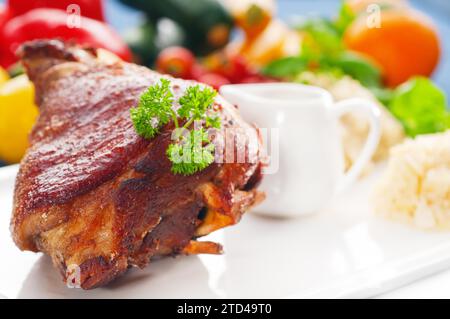 Original German BBQ Schweinshaxe serviert mit Kartoffelpüree und Sauerkraut, frisches Gemüse im Hintergrund, LECKERES ESSEN IM PORTFOLIO, Essen Stockfoto