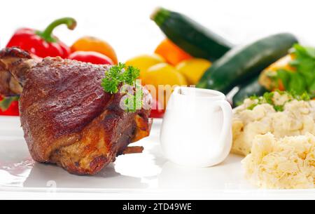 Original German BBQ Schweinshaxe serviert mit Kartoffelpüree und Sauerkraut, frisches Gemüse im Hintergrund, LECKERES ESSEN IM PORTFOLIO, Essen Stockfoto