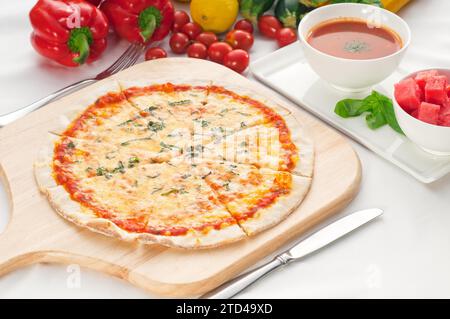 Italienische Original-Pizza mit dünner Kruste Margherita mit Gazpacho-Suppe und Wassermelone auf der Seite und Gemüse auf dem Hintergrund, Lebensmittelfotografie Stockfoto