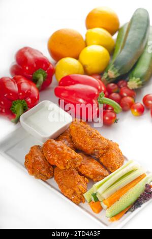 Klassische Buffalo Chicken Wings serviert mit frischem Pinzimonio und Gemüse im Hintergrund, KÖSTLICHERE SPEISEN IM PORTFOLIO, Lebensmittelfotografie Stockfoto