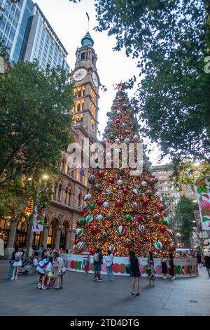 Riesiger, voll dekorierter Weihnachtsbaum im Freien, am Martin Place, Sydney, Australien, im Sommer auf der südlichen Hemisphäre. Menschen, die sich zusammenfinden. Stockfoto