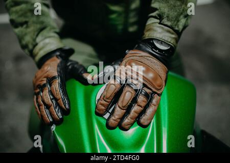 Ein Motorradfahrer zeigt seine braunen Lederhandschuhe für eine Tour zur Kamera, Moto Ausrüstung Stockfoto