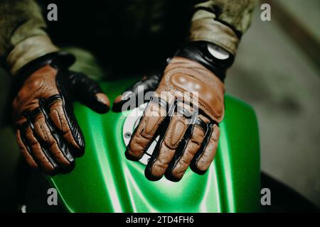 Ein Motorradfahrer zeigt seine braunen Lederhandschuhe für eine Tour zur Kamera, Moto Ausrüstung Stockfoto